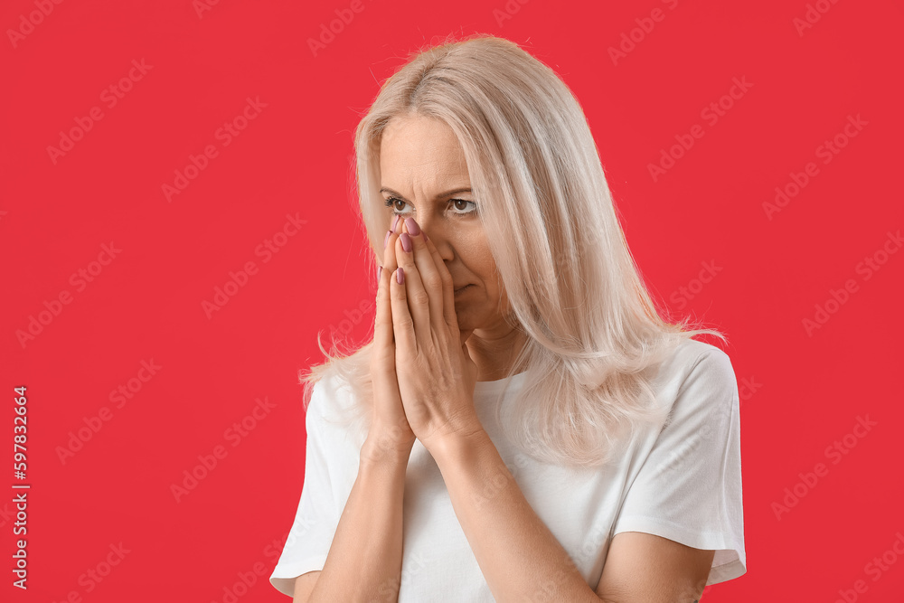Mature woman praying on red background, closeup Mature woman praying on red background, closeup