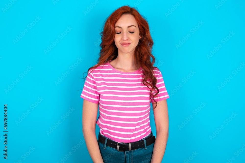young redhead woman wearing striped T-shirt over blue background nice-looking sweet charming cute attractive lovely winsome sweet peaceful closed eyes young redhead woman wearing striped T-shirt over blue background nice-looking sweet charming cute attractive lovely winsome sweet peaceful closed eyes