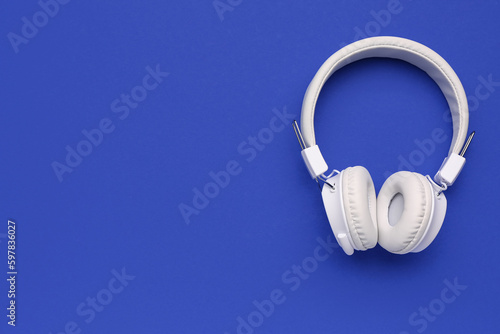 Modern white headphones on blue background