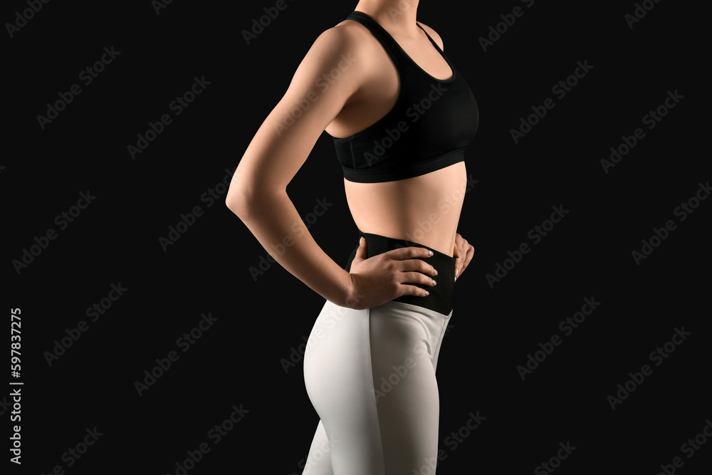 Fototapeta premium Sporty young woman in leggings on black background