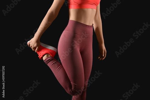 Sporty young woman in leggings on black background photo