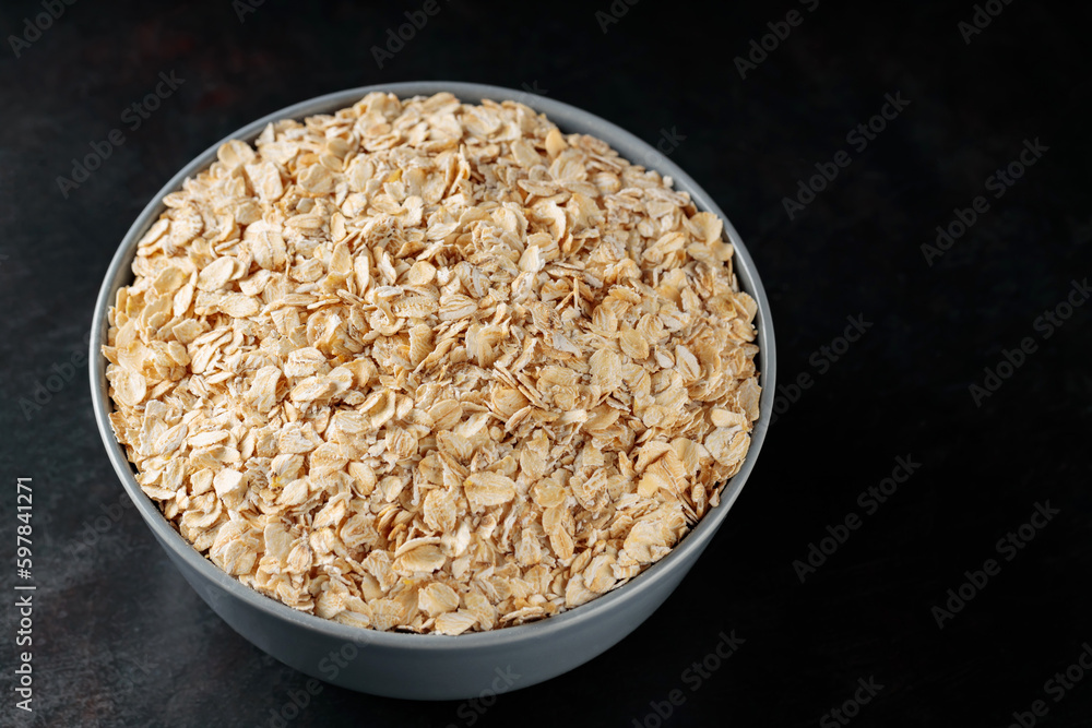 Oat flakes bowl on a dark background. Dry rolled oatmeal for a healthy breakfast. Top view. Copy space Oat flakes bowl on a dark background. Dry rolled oatmeal for a healthy breakfast. Top view. Copy space