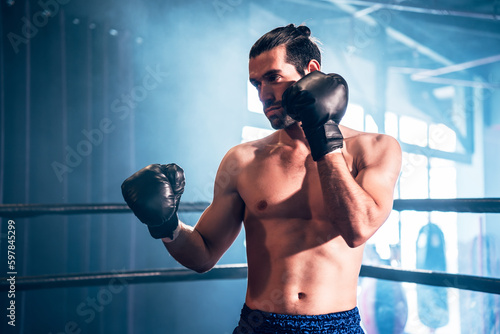 Strong caucasian sportsman wearing boxing gloves for training muay thai at gym, Active male workout at sport club for cardio and body strength. Health and lifestyles concept. © Platoo Studio