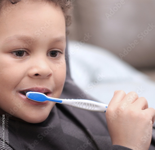little boy brushing his teeth with an electric tooth brush stock image with grey background stock photo
