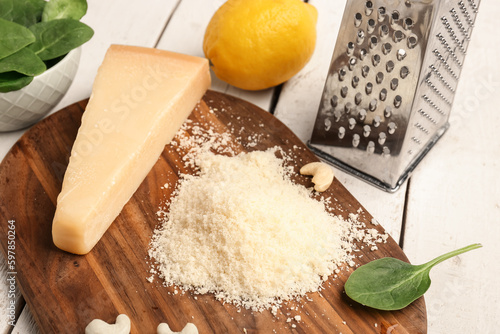 Board with tasty Parmesan cheese on light wooden background, closeup