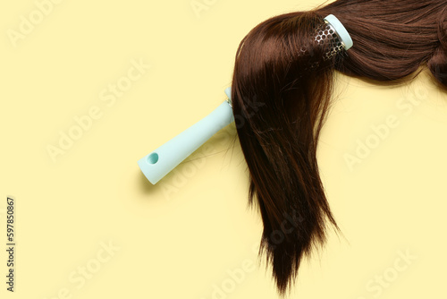 Brown hair with round brush on yellow background
