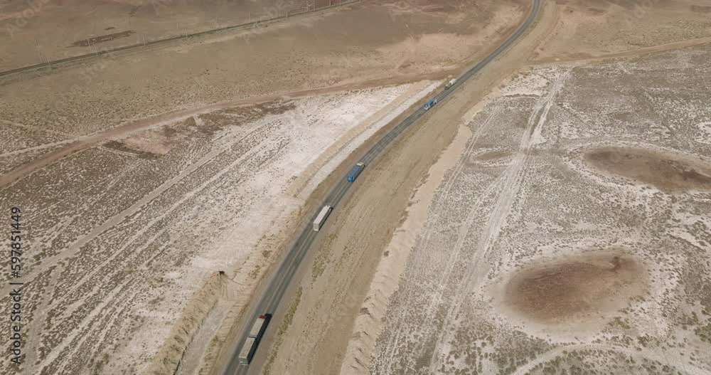 Semi Trucks with white trailer and cab driving, traveling alone by arid hilly landscape, highway perspective follow vehicle drone view. Freeway trucks traffic Semi Trucks with white trailer and cab driving, traveling alone by arid hilly landscape, highway perspective follow vehicle drone view. Freeway trucks traffic