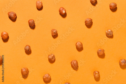 Shelled hazelnuts on orange background, closeup
