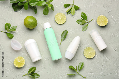 Different deodorants, leaves and lime on grunge background