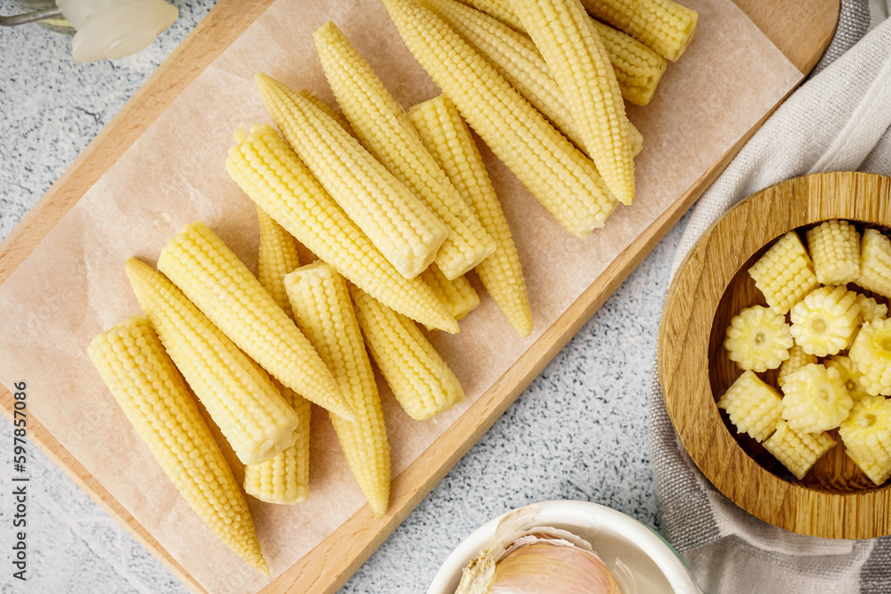 Wooden board with tasty canned corn cobs on light background Wooden board with tasty canned corn cobs on light background