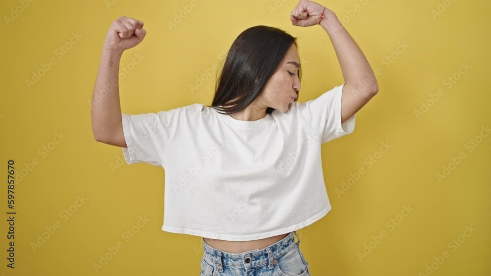 Young beautiful hispanic woman smiling confident doing strong gesture with arms over isolated yellow background Young beautiful hispanic woman smiling confident doing strong gesture with arms over isolated yellow background