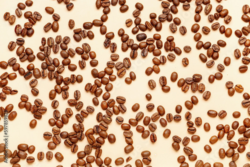 Scattered coffee beans on pale yellow background