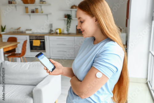 Bild auf Leinwand Woman with glucose sensor using mobile phone for measuring of blood sugar level