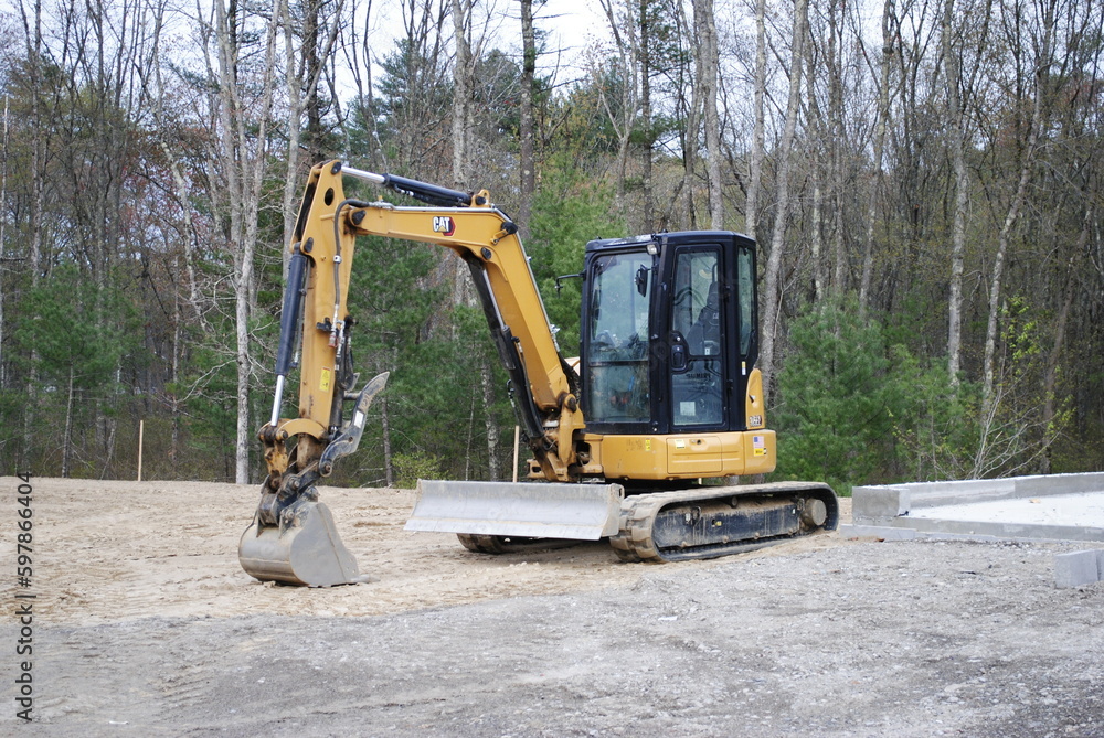 Small CAT bulldozer bucket excavator parked on active construction site in the sand isolated Small CAT bulldozer bucket excavator parked on active construction site in the sand isolated