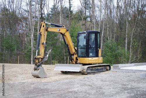 Small CAT bulldozer bucket excavator parked on active construction site in the sand isolated