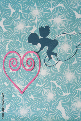 stylized cupid or putto or eros with wings and wire heart on floral scrapbook paper