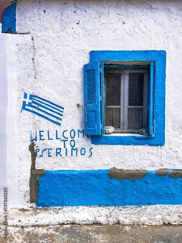 Welcome to Pserimos text in english language and national Greek flag painted on a white washed wall, blue window frame. Travel destination concept. Typical Greece style background with copy space. photo