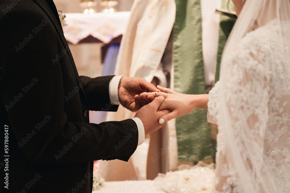 Fototapeta premium The bride and groom exchange rings in the church, the sacrament of the wedding