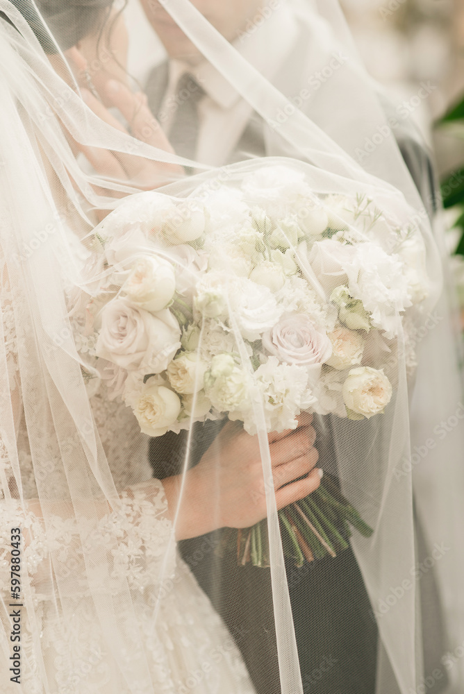wedding bouquet in the hands of the bride under the veil