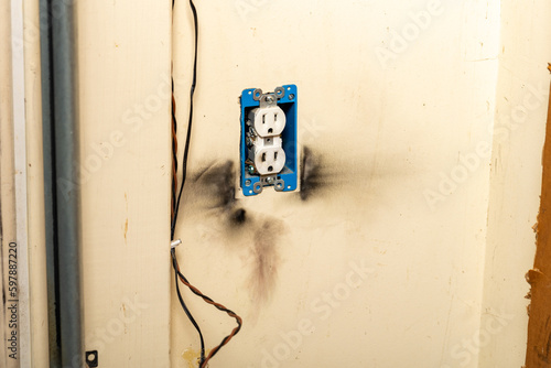 Electrical outlet with burn marks on wall from short circuit. photo