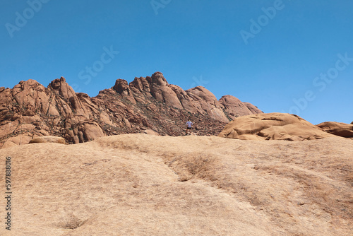 Woman looking up at imposing rock mountain in Spitzkoppe Namibia