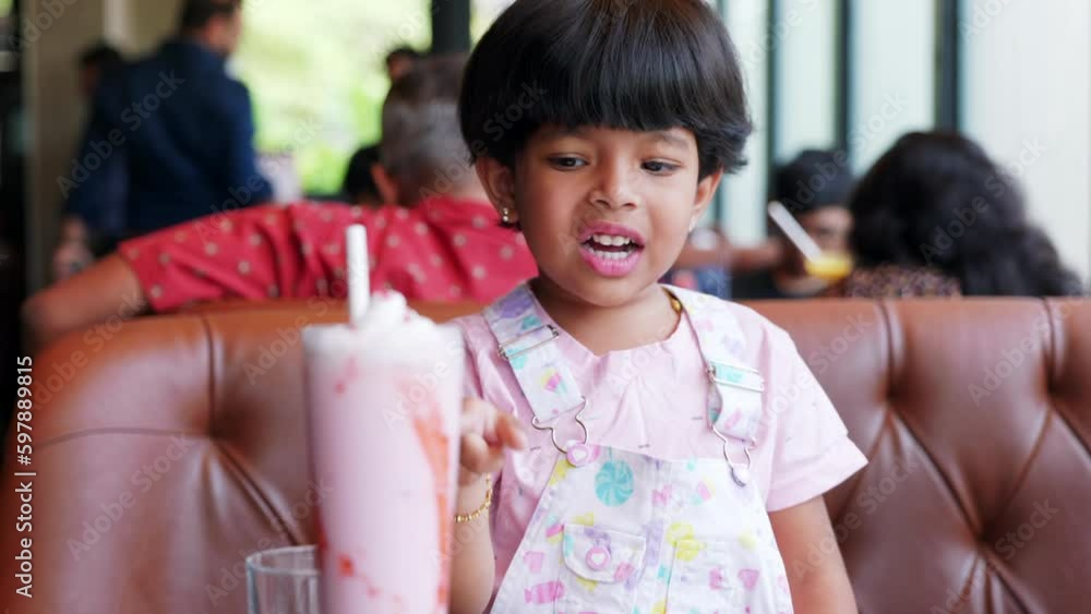 Girl put straw in strawberry juice and focusing on girl and juice sitting in hotel brown sofa Girl put straw in strawberry juice and focusing on girl and juice sitting in hotel brown sofa