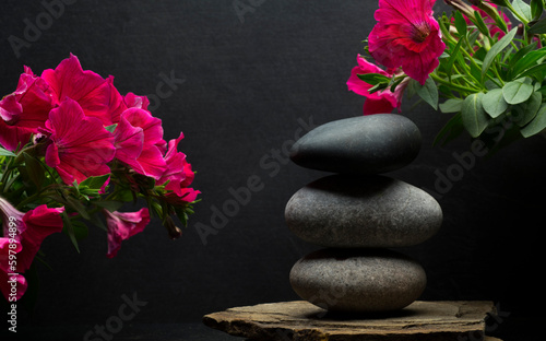 stones and flowers for podium background.stack of zen stones on dark background with shadows and pink flowers.