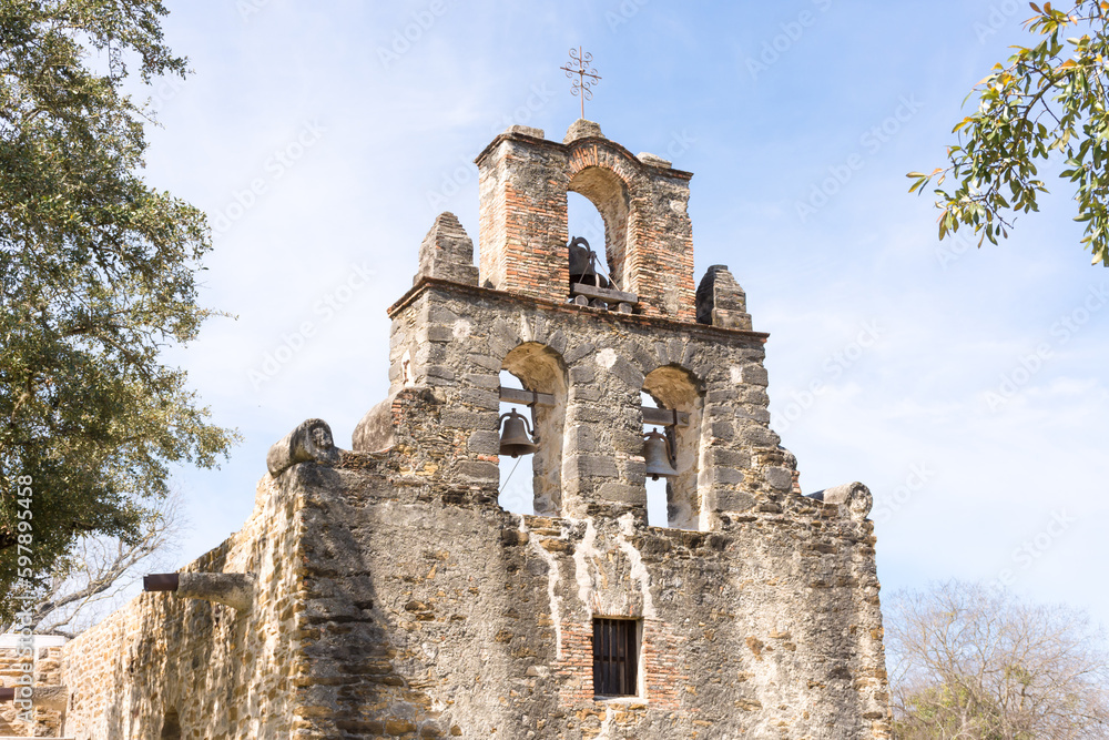 The Bells of Mission Espada set under stone arches with cross, San Antonio, Texas