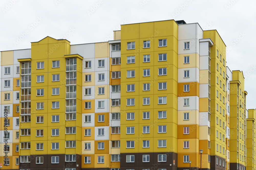 Multicoloured high-rise residential buildings in affluent areas. Multi-apartment multi-storey building with a multicolored facade against a blue sky background. Modern design. Buying a home.