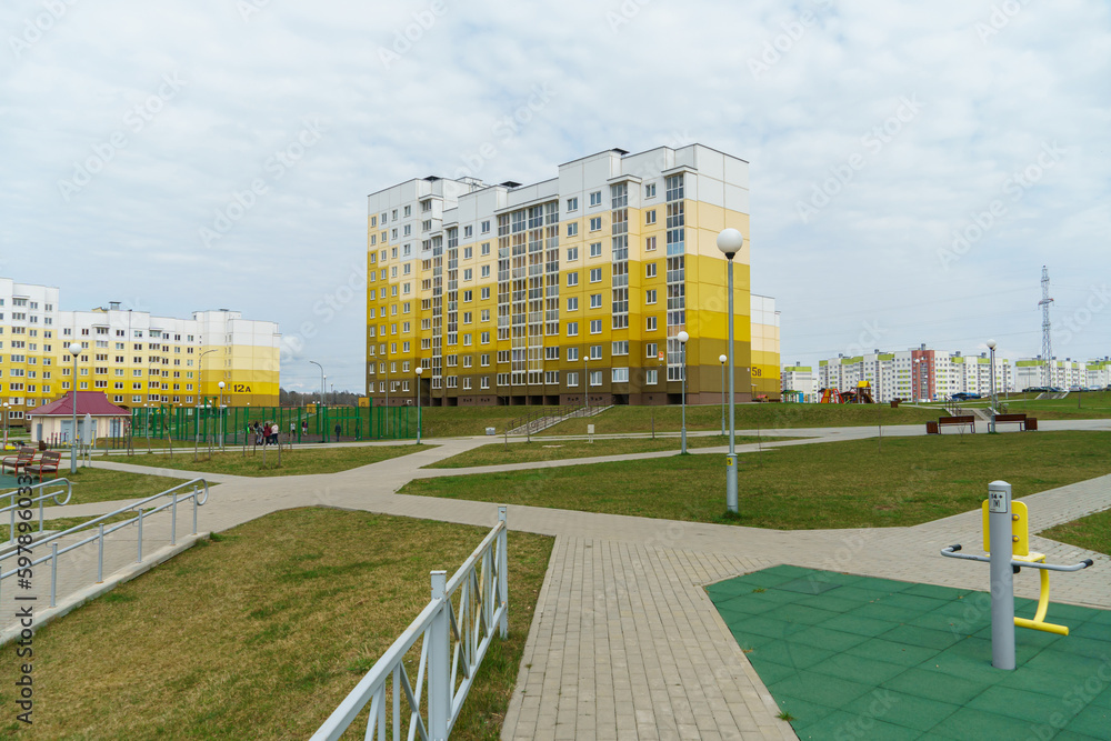 Modern well-maintained residential area with tall multi-colored houses. A new sidewalk and a playground in the courtyard of the house. Lending to the population and renting housing