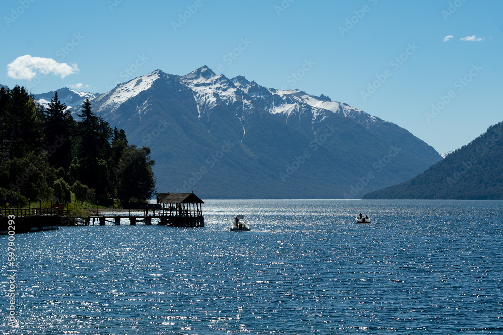Lake between mountains with snow-capped peaks, dock on the water, no people, daytime
