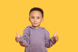 African-American boy showing thumbs up on yellow background