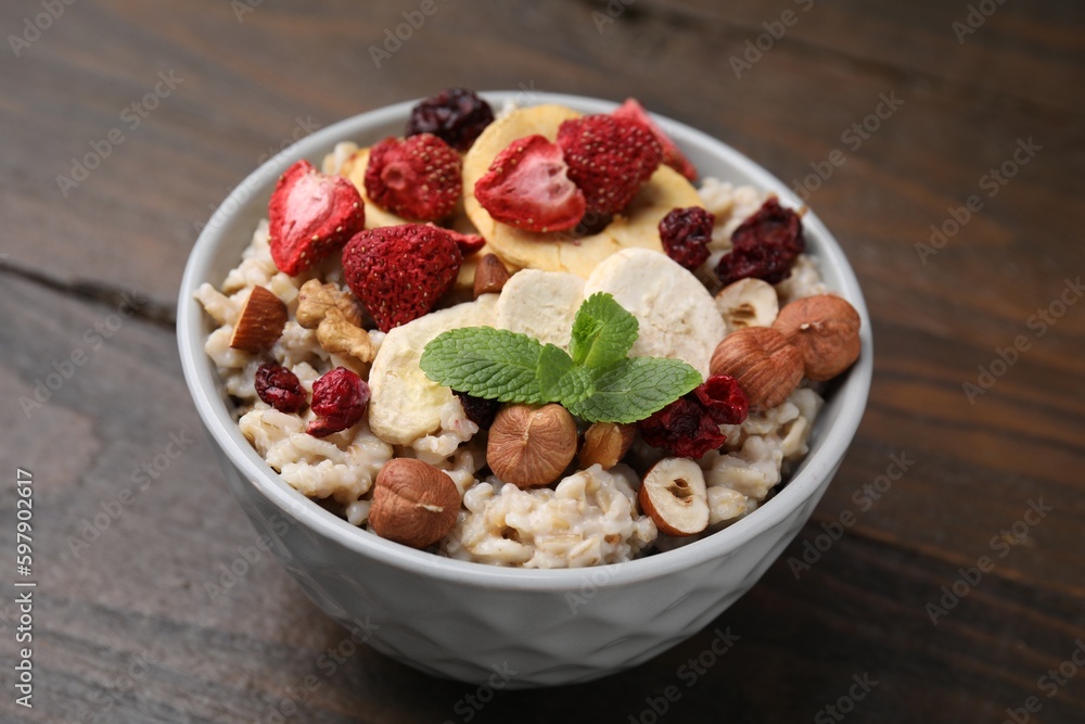 Oatmeal with freeze dried fruits, nuts and mint on wooden table Oatmeal with freeze dried fruits, nuts and mint on wooden table