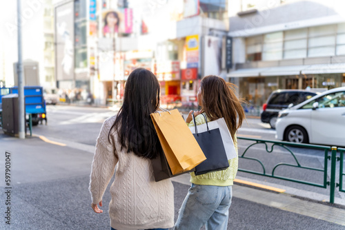 Happy Asian woman friends walking and shopping together at Shibuya district, Tokyo, Japan in autumn. Attractive girl enjoy and fun outdoor lifestyle walking and travel city street on holiday vacation.