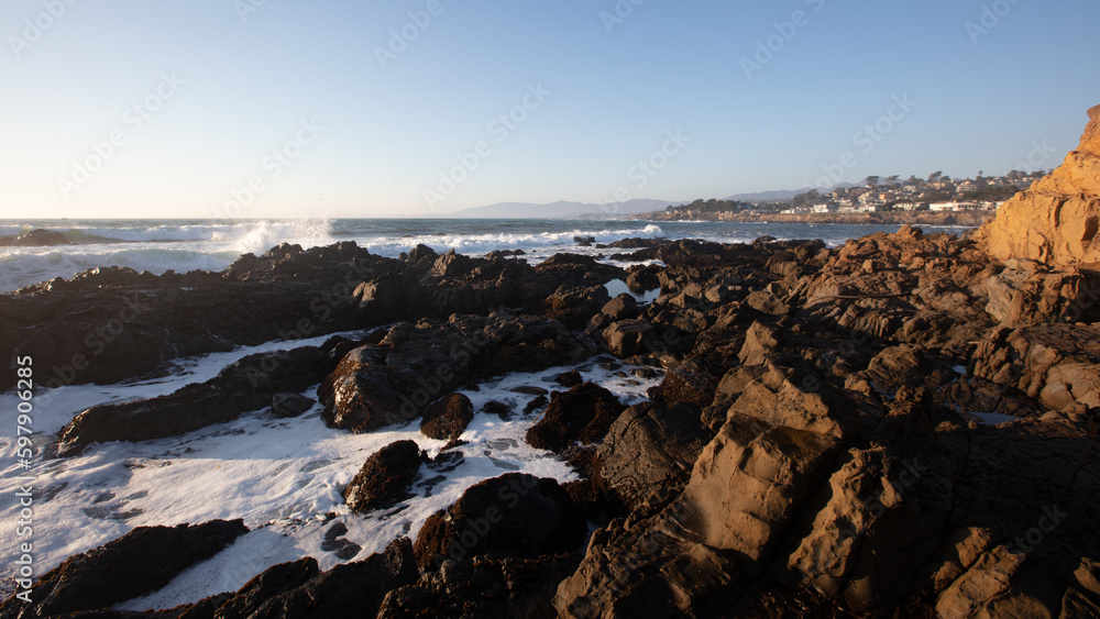 Seaspray and seafoam on the rocky central California coastline during golden hour at Cambria California United States
