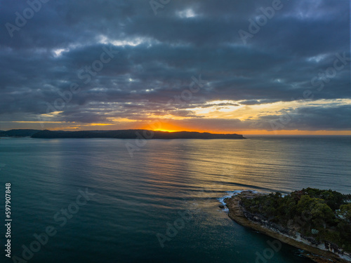 Aerial sunrise seascape with calm seas and a mix of high and low cloud