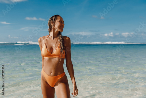 Attractive tanned woman in bikini at ocean beach.