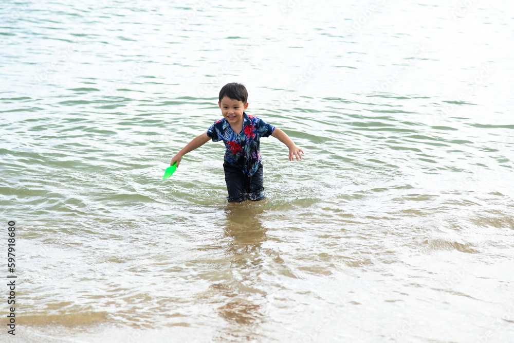 happy little asian boy on swimming on tropical summer beach