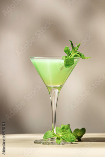 Grasshopper green alcoholic cocktail drink with mint liqueur, cream, ice and fresh mint. Beige background, hard light, shadow pattern, copy space