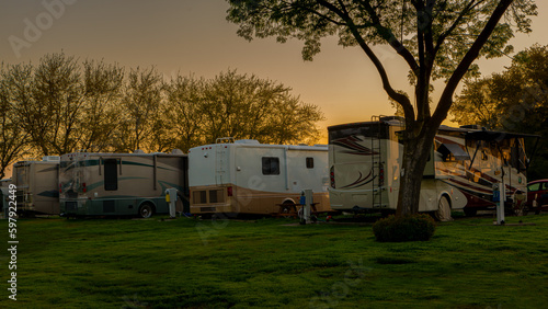 Rv motorhomes parked in a row at campsite in grass asunrise