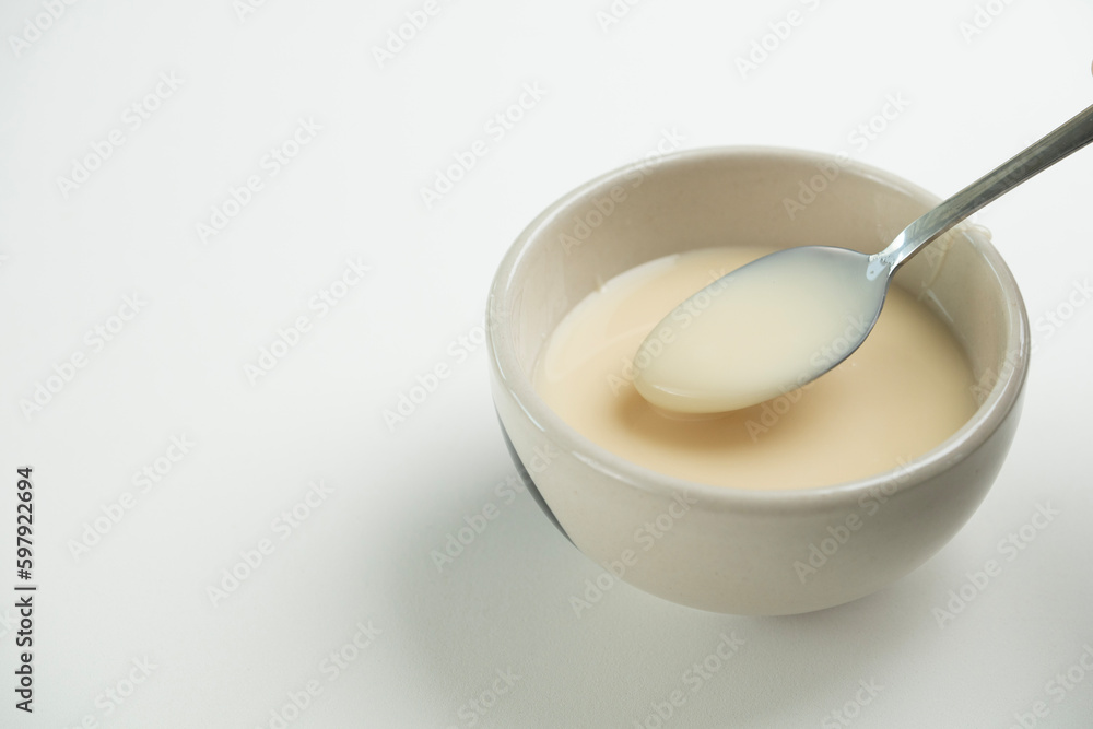 close up of condensed milk with spoon isolated on white background, food ingredients concept close up of condensed milk with spoon isolated on white background, food ingredients concept