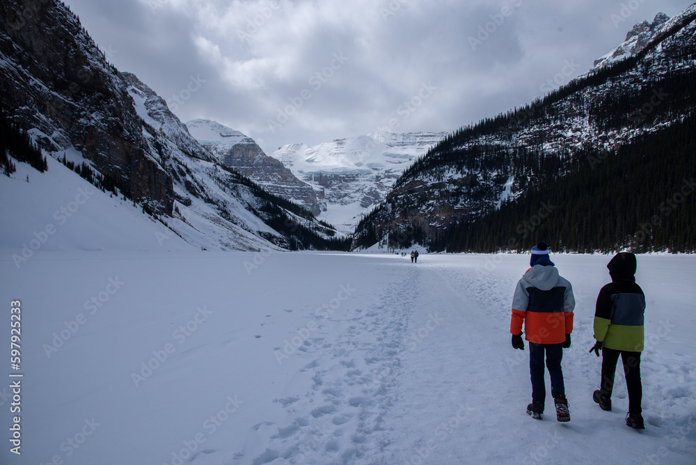 Two kids walking on a Frozen Lake Louise enjoying Canadian winter months. Wonderful winter landscapes of Canada. 