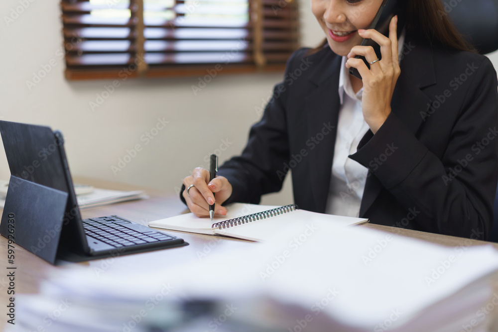 Secretary concept, Female secretary talking on phone with executive and taking notes in notebook Secretary concept, Female secretary talking on phone with executive and taking notes in notebook