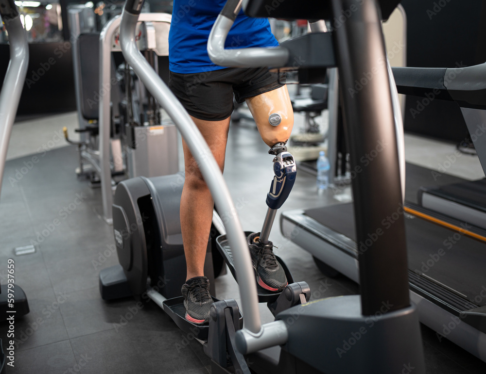 Low angle view at woman with prosthetic leg use exercise machine at fitness gym Low angle view at woman with prosthetic leg use exercise machine at fitness gym
