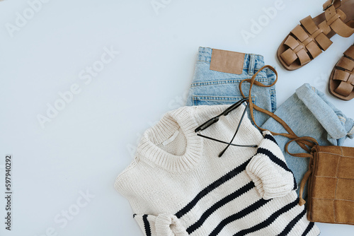 Aesthetic casual fashion composition with female clothes and accessories. Striped sweater, leather sandals, suede bag, jeans, sunglasses. Flat lay, top view.