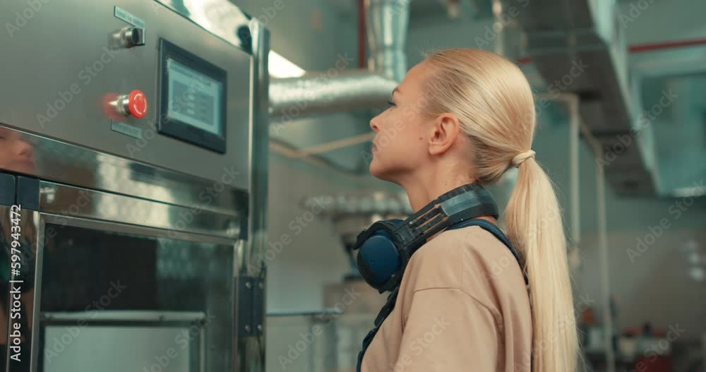 confident beautiful blonde woman in uniform controlling, turning on robotic machine, caucasian young lady in protective workwear uniform mastered the male profession. feminism concept confident beautiful blonde woman in uniform controlling, turning on robotic machine, caucasian young lady in protective workwear uniform mastered the male profession. feminism concept
