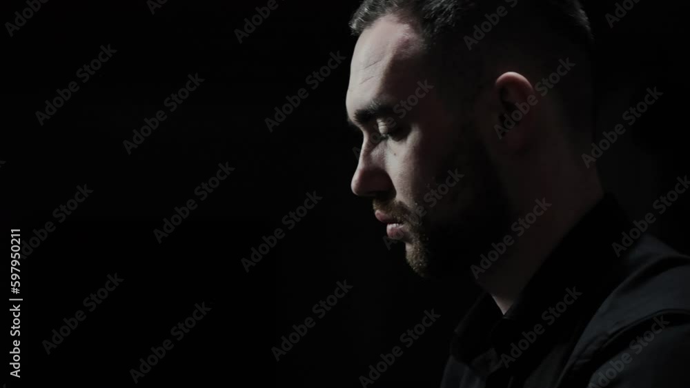 The face of a pianist playing the piano. Emotions of a man while playing the piano. Close-up of a face in a dark room, profile view. The face of a pianist playing the piano. Emotions of a man while playing the piano. Close-up of a face in a dark room, profile view.