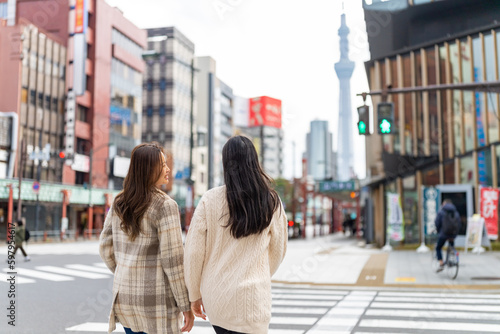 Canvas Print Asian woman friends crossing street crosswalk with crowd of people during travel together at Asakusa, Tokyo, Japan in autumn