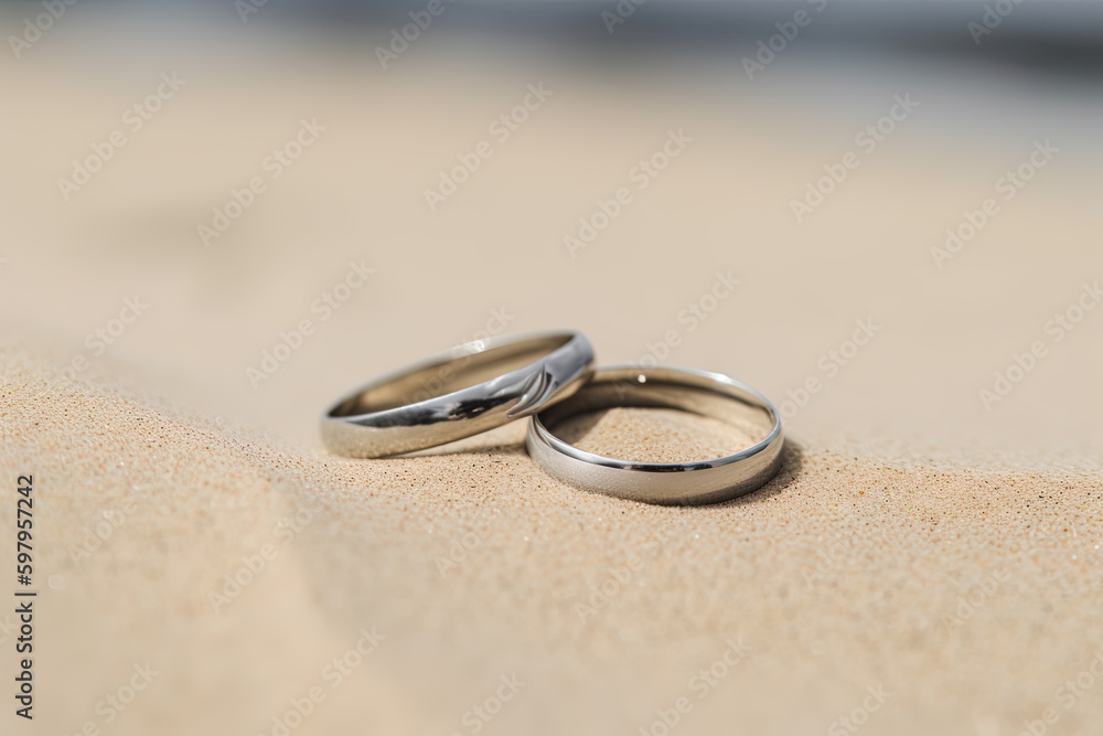 Two wedding rings in the sand on the background of a beach and sea. Created with Generative AI Technology Two wedding rings in the sand on the background of a beach and sea. Created with Generative AI Technology