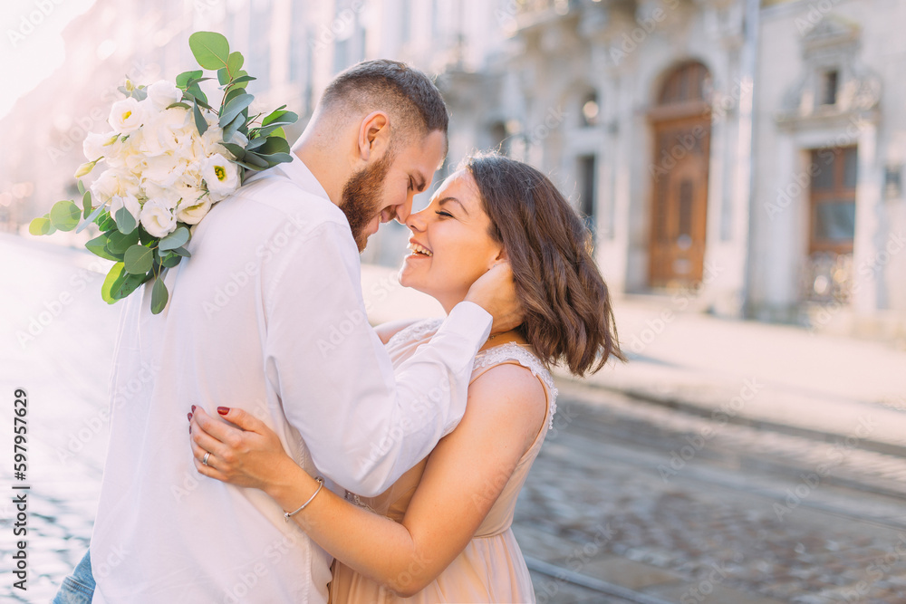 Fototapeta premium happy bride and groom embrace while walking through the old city, the couple looks at each other and smiles